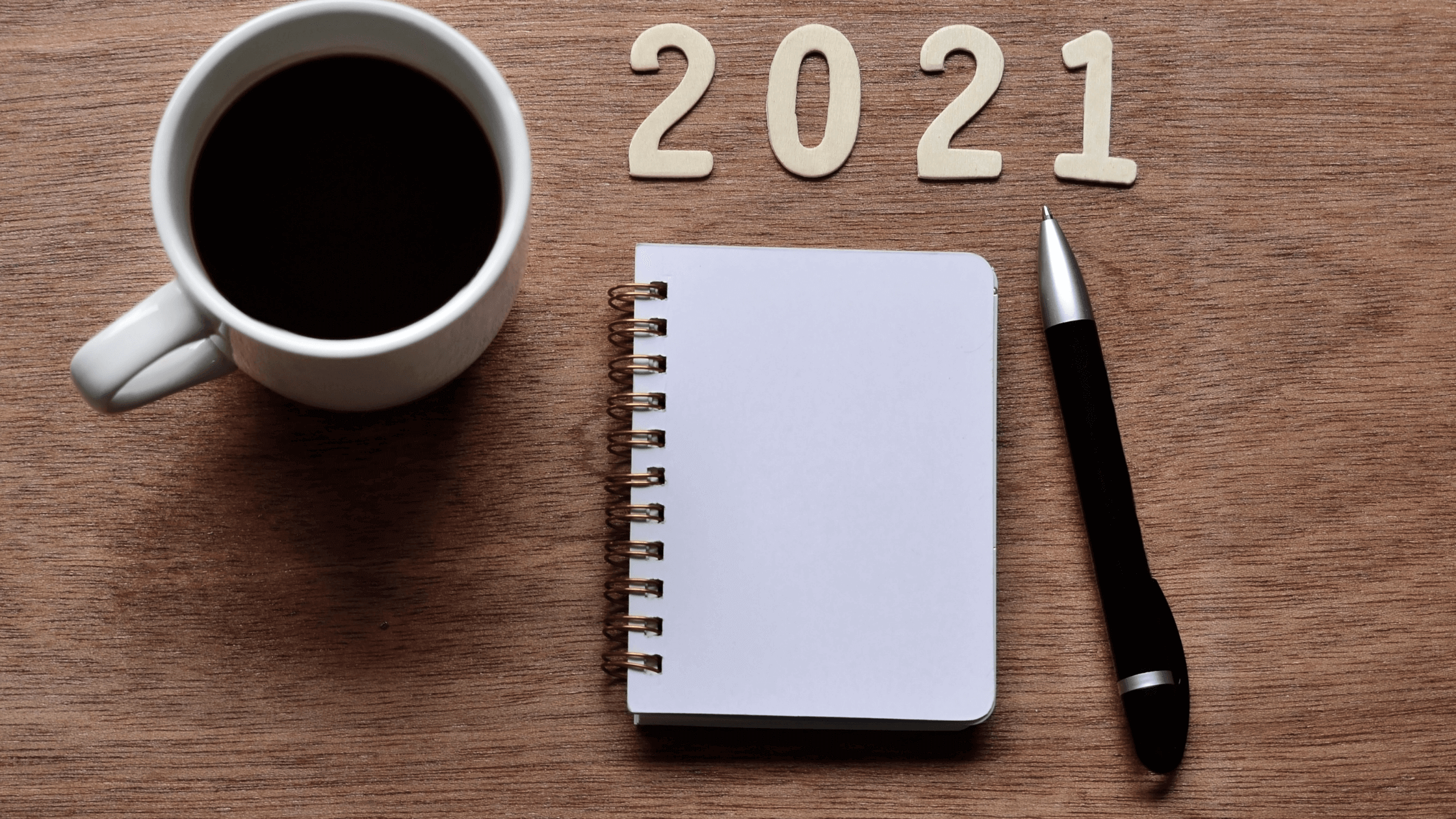 Eine Tasse Kaffee, ein Notizblock und ein Stift zusammen mit Schriftzug "2021"